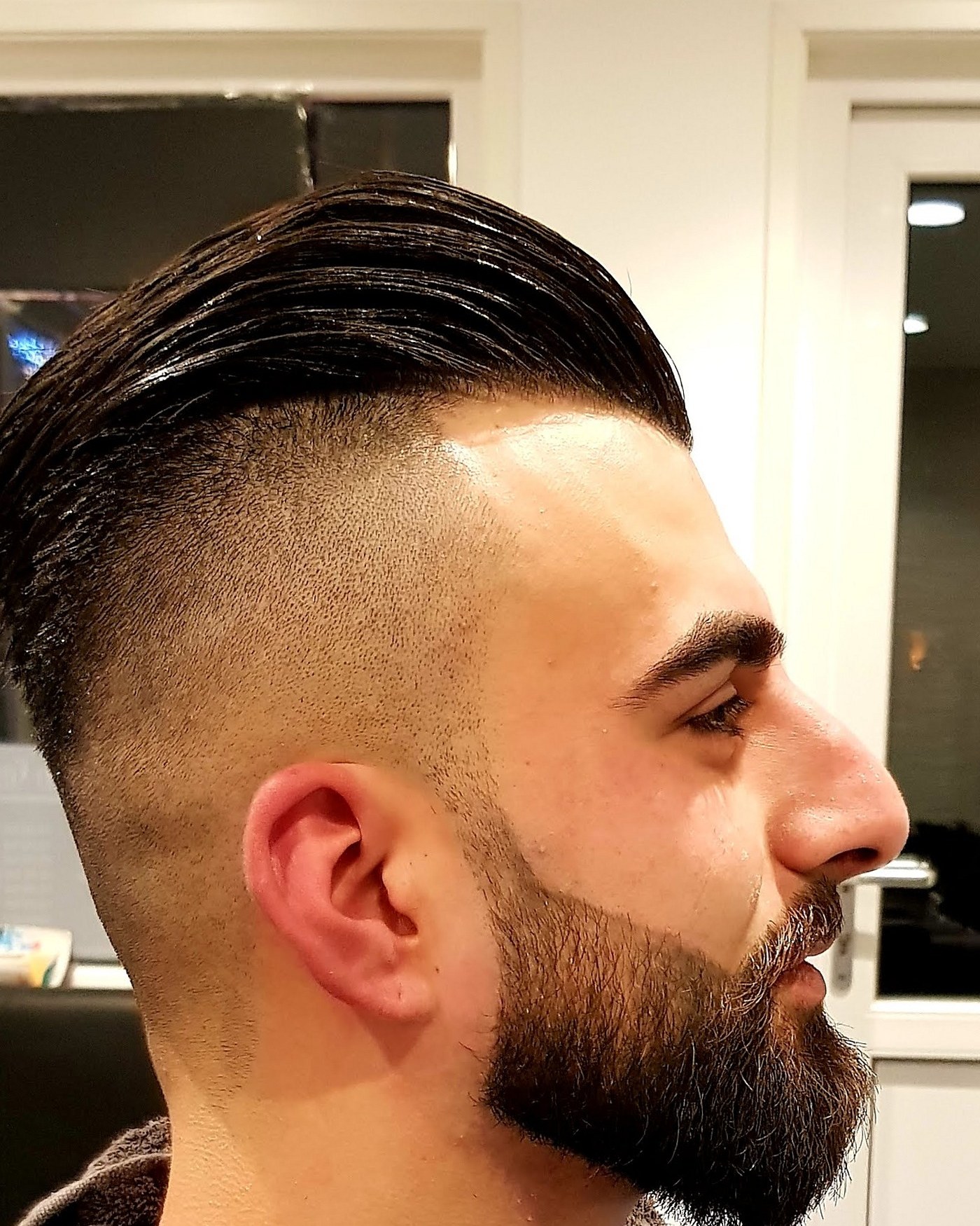 Klant in profiel met kortgeschoren zijkanten, lang haar bovenop en een volle baard